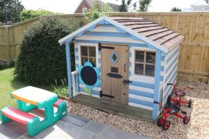 una pequeña casa de juegos de madera con un triciclo en un patio en Willow-Oak, en Seaview