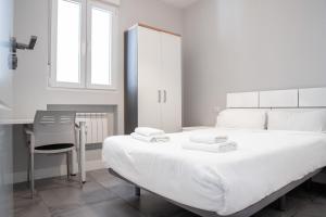 um quarto com uma grande cama branca e uma cadeira em Apartamento de 4 dormitorios en Retiro em Madri