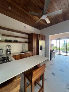 a kitchen with a large white counter top and wooden ceilings at Casa Celajes Sol in Nosara