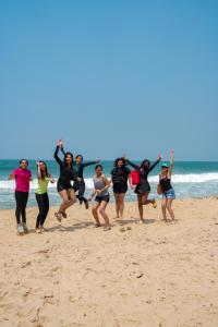 Eine Gruppe Frauen springt am Strand in der Unterkunft House Of Surf Hostel for Women in Varkala