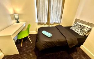 a bedroom with a bed and a desk and a green chair at Bethnal Green Rooms R4 in London