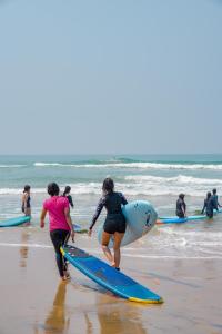 a group of people walking on the beach with surfboards at House Of Surf Hostel for Women in Varkala