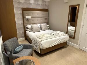 ein Schlafzimmer mit einem Bett, einem Spiegel und einem Stuhl in der Unterkunft The Fig Tree Hotel in Shanklin