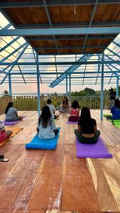 eine Gruppe von Leuten, die auf dem Boden sitzen und Yoga machen in der Unterkunft House Of Surf Hostel for Women in Varkala