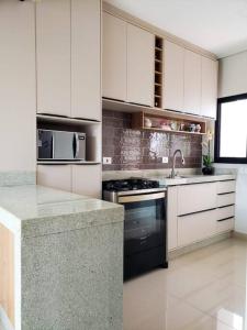 uma cozinha com armários brancos e um forno de fogão preto em Sua casa em Foz, localização incrível em Foz do Iguaçu