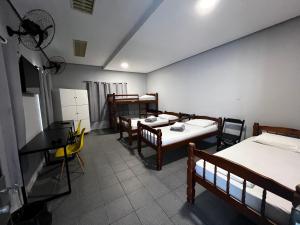 a room with three beds and a table and chairs at Family Hostel in São Paulo
