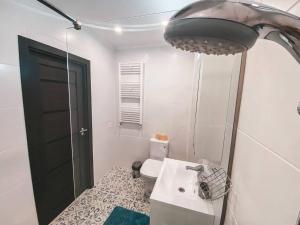 Baño blanco con lavabo y aseo en City Center Apartment en Chisináu