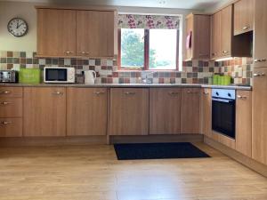 a kitchen with wooden cabinets and a clock on the wall at Water Mill Vacations Goldfinch - Pet Friendly in Newport