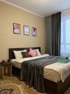 a bedroom with a bed with pillows and a window at Комфортабельные апартаменты по Туран in Taldykolʼ