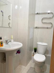 a white bathroom with a toilet and a sink at Комфортабельные апартаменты по Туран in Taldykolʼ +13 photos