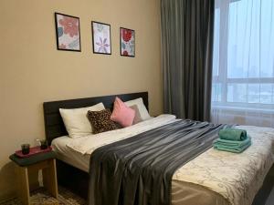 a bedroom with a bed with pillows and a window at Комфортабельные апартаменты по Туран in Taldykolʼ