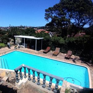 a swimming pool with two chairs and a gazebo at Rose Holiday Home in Durban