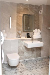 a bathroom with a sink and a toilet and a mirror at The Fig Tree Hotel in Shanklin