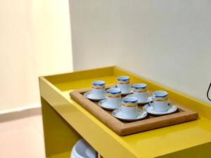 a tray with nine cups and saucers on a yellow table at 2 Quartos Completo Barato in Brasilia