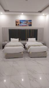 3 Betten in einem Zimmer mit weißen Marmorböden in der Unterkunft بيست تريب فالنسيا in Dschāzān