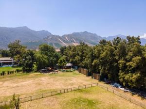 un champ planté d'arbres et de montagnes en arrière-plan dans l'établissement Franschhoek Cottages, à Franschhoek