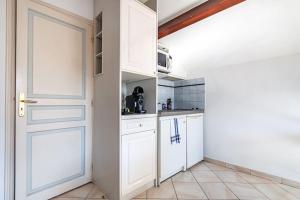 una cocina con armarios blancos y una puerta en Cosy Revy - Proche Paris, en Saint-Michel-sur-Orge