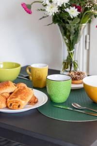 una mesa con platos de comida y tazas y un jarrón con flores en Cosy Revy - Proche Paris, en Saint-Michel-sur-Orge