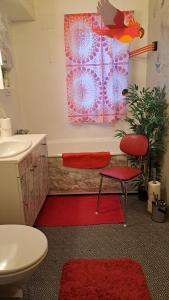 baño con silla roja, lavamanos y alfombra roja en Kule gule huset en Svolvær