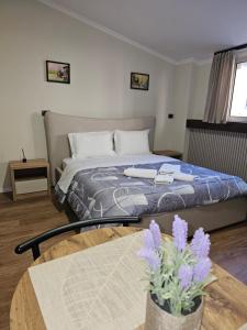 una camera con letto e tavolo con fiori viola di Vila TAFA Apartments a Tirana