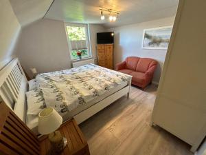 a small bedroom with a bed and a red chair at Auszeit! in Büdelsdorf