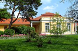 una casa amarilla con un jardín delante de ella en Ensana Vila Trajan, en Piešťany