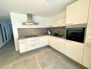 a kitchen with white cabinets and a black appliance at DaCasa-Appartement: zentral/SmartTV/24h Check in in Tamm