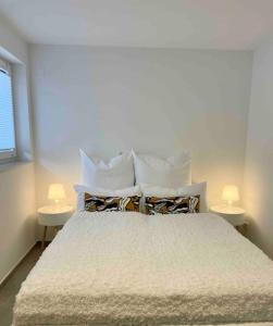a bedroom with a bed with pillows and two lamps at DaCasa-Appartement: zentral/SmartTV/24h Check in in Tamm
