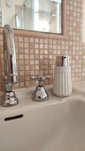 a bathroom sink with a chrome faucet and a mirror at La casa del Mago camere e appartamenti in Pissignano