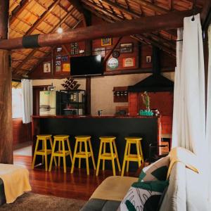 un bar avec quatre tabourets jaunes dans une pièce dans l'établissement Fazenda Hirt, à Três Coroas