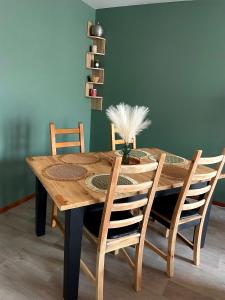 einem hölzernen Esstisch mit 4 Stühlen und einer grünen Wand in der Unterkunft CHARMANT APPARTEMENT AVEC GRANDE CAPACITÉ D’ACCUEIL in Saint-Jacques-de-la-Lande