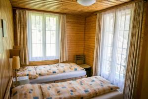 a bedroom with two beds and two windows at Hotel Alpenhof in Kerns