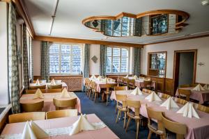 a dining room with tables and chairs and windows at Hotel Alpenhof in Kerns