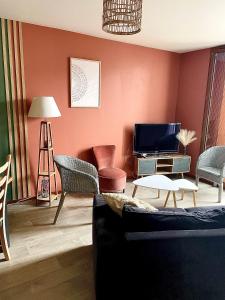ein Wohnzimmer mit einem Sofa und einem TV in der Unterkunft CHARMANT APPARTEMENT AVEC GRANDE CAPACITÉ D’ACCUEIL in Saint-Jacques-de-la-Lande