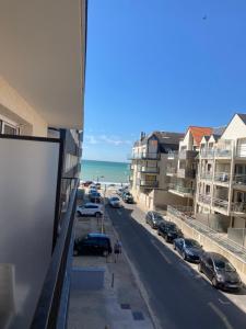 Una vista de una calle con autos estacionados y el océano. en la rafale, en Fort-Mahon-Plage
