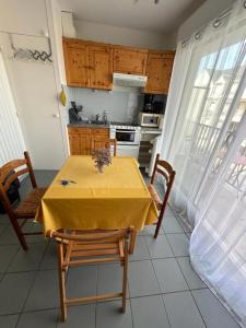 una cocina con una mesa con un mantel amarillo. en la rafale, en Fort-Mahon-Plage 5 fotos más