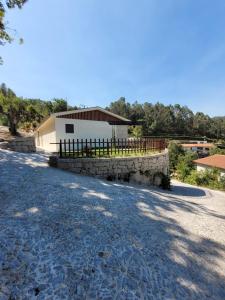a house with a fence and a stone wall at Quinta do Bento in Vieira do Minho
