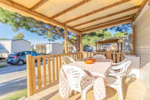 a wooden deck with a table and chairs on it at MOBILHOME SOLEIA NEUF 2023 MAR ESTANG SIBLU VILLAGE Canet-en-Roussillon in Canet-en-Roussillon