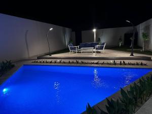 una piscina azul en un patio trasero por la noche en شاليهــات داكــن, en Butainiyāt