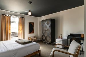 a bedroom with a bed and a chair and a piano at The Darby in Beach Lake