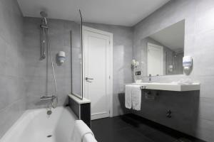 Un baño con bañera, lavabo y espejo. en Hotel La Palma de Llanes, en Llanes