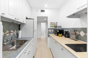 eine Küche mit weißen Schränken und einer Spüle aus Edelstahl in der Unterkunft Welcoming Airbnb Walkig distance to Las Olas Blvd in Fort Lauderdale