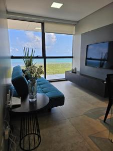 Flat #2506 BARRA HOME STAY في ريسيفي: غرفة معيشة مع أريكة زرقاء وطاولة