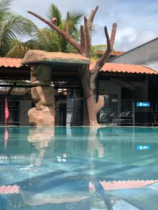 a pool at a resort with a fake tree at Pousada Aguas Quentes in Barra do Garças