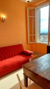 a living room with a red couch and a table at La casa del Mago camere e appartamenti in Pissignano