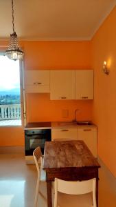 cocina con mesa de madera, armarios blancos y ventana en La casa del Mago camere e appartamenti en Pissignano