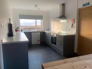 a large kitchen with white counters and a window at Hillview Portree Isle of Skye Self Catering House in Portree