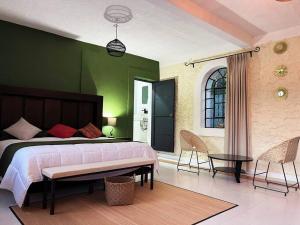 a bedroom with a large bed and a green wall at Rancho Huemac in Zimapán