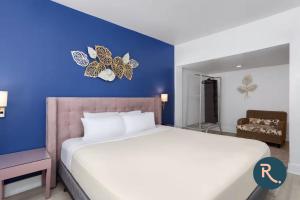 a bedroom with a large bed with a blue wall at Roami at Hotel Astor in Miami Beach +27 photos