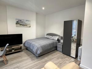 1 dormitorio con 1 cama y TV de pantalla plana en El Murrino Apartments, en Bournemouth
